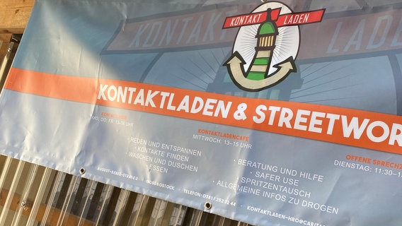 Ein Banner des Kontaktladens in Rostock, der verschiedene Leistungen für Suchtkranke anbietet. © NDR Foto: Jakob Gaberle