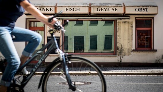 Ein Radfahrer faehrt an einem geschlossenen Lebensmittelgeschaeft vorbei, aufgenommen in Crimmitschau. © picture alliance / photothek Foto: Florian Gaertne
