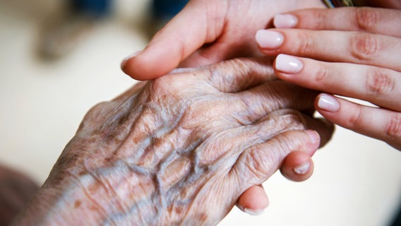 Hände einer jungen Frau halten die Hände einer alten Frau in den Ihren. © dpa-Bildfunk Foto: Christophe Gateau/dpa