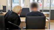 Die Rechtsanwältin und der Angeklagte im Prozess wegen dreifachen Mordes warten im Gerichtssaal auf den Prozessbeginn. © dpa-Bildfunk Foto: Bernd Wüstneck