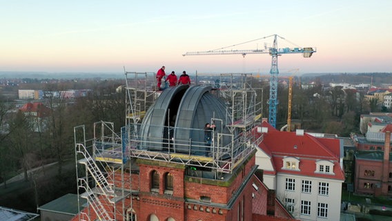 Arbeiter stehen in rund 40 Metern Höhe auf einem Gerüst und bauen die Rolltore der Holzkuppel über der Sternwarte in Greifswald aus. © NDR Foto: NDR