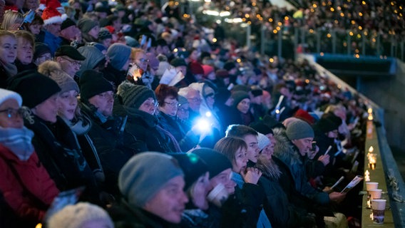 Menschen nehmen beim Weihnachtssingen im Rostocker Ostseestadion © dpa Foto: Frank Hormann