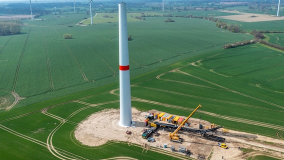Der erste Teil einer insgesamt 238 Meter hohen Windkraftanlage steht in Questin. Drohnenaufnahme vom Aufbau. © Jens Büttner/dpa Foto: Jens Büttner/dpa