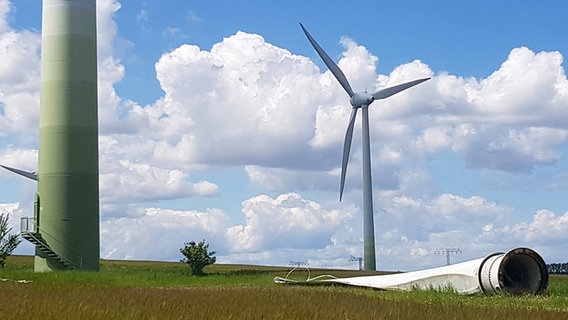 Neben dem Turm einer Windkraftanlage bei Wismar liegt ein Windradflügel auf einem Feld. Im Hintergrund sind zwei weitere Windräder zu sehen. © Christoph Woest Foto: Christoph Woest