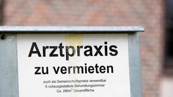 Ein Schild mit der Aufschrift "Arztpraxis zu vermieten" steht vor einem Gebäude im Landkreis Heidekreis. © picture alliance/dpa Foto: Moritz Frankenberg