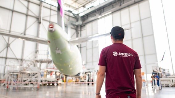 Ein Airbus-Mitarbeiter steht vor einem Flugzeug. © picture alliance/Daniel Reinhardt/dpa Foto: Daniel Reinhardt