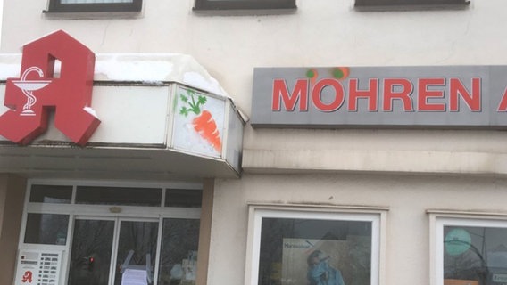 Auf einem Schild steht "Möhren" und ein Apothekenlogo ist zu sehen. In der Mitte eine gesprühte Möhre. © Rüben gegen Rassismus 