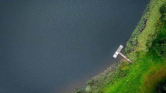 Eine Luftaufnahme zeigt den Otterstedter See, an dessen Ufer ein Steg ins Wasser führt. © dpa - picture alliance Foto: Sina Schuldt
