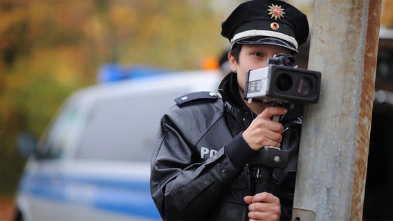 Eine Polizistin misst mit einer Laser-Pistole die Geschwindigkeit der vorbeifahrenden Autos. © dpa Foto: Julian Stratenschulte