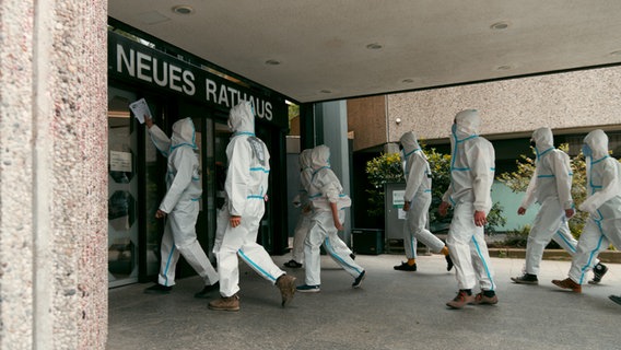 Demonstranten in Maleranzügen gehen auf den Eingang des Göttinger Rathauses zu. © Hendrik Bammel Foto: Hendrik Bammel