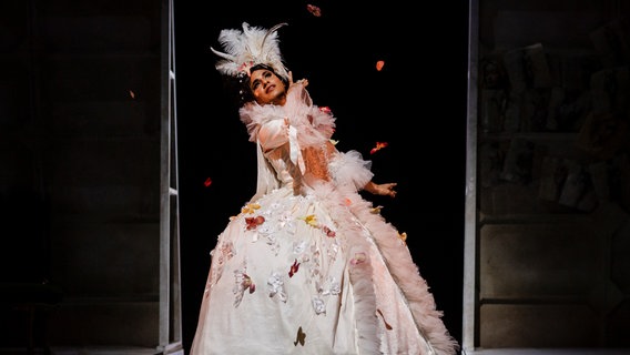 Händelinterpret Samuel Marino steht in einem Kleid als Zambinella auf der Bühne und lächelt. © Göttinger Händelfestspiele Foto: Alciro Theodoro Da Silva