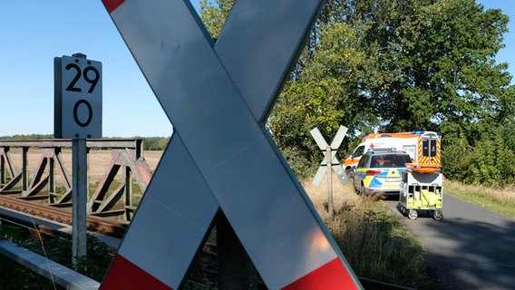 Hinter einem Andreaskreuz an einem unbeschrankten Bahnübergang sind Einsatzfahrzeuge von Rettung und Polizei zu sehen. © Peter Steffen 