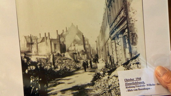 Willi Meyer hält ein historisches Foto der zerstörten Leopoldstraße in der Hand. © NDR Foto: Lydia Haake