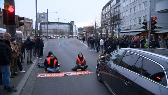 Aktivisten und Aktivistinnen haben sich auf einer Straße festgeklebt. © NDR 
