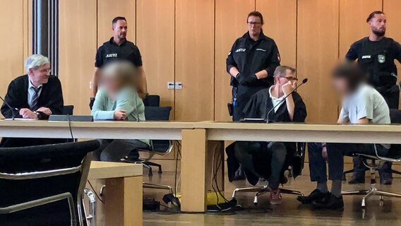 Die beiden Angeklagten mit ihren Anwälten und Justizbeamten im Gerichtssaal in Braunschweig © NDR 
