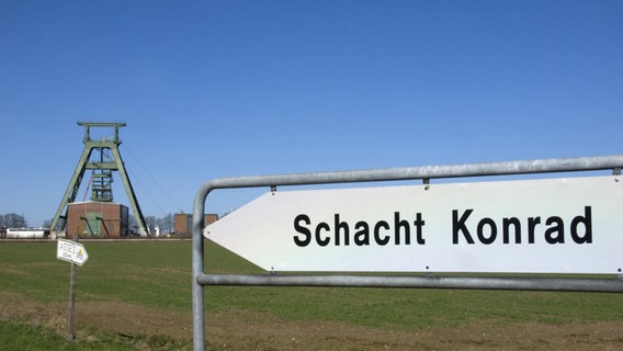 Auf einem Wegweiser vor einem Förderturm steht "Schacht Konrad". © picture alliance/Bildagentur-online/McPhoto-Scholz 