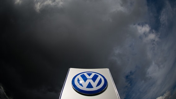 Dunkle Wolken ziehen über ein VW-Logo am Tor vom VW Werk in Wolfsburg. © dpa Foto: Julian Stratenschulte