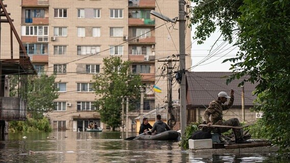 Ein Mann erreicht sein überflutetes Haus. Infolge des verheerenden Hochwassers nach der Zerstörung des Kachowka-Staudamms sind im russisch besetzten Teil des südukrainischen Gebiets Cherson mehrere Menschen ums Leben gekommen. © dpa-Bildfunk Foto: Evgeniy Maloletka/AP/dpa