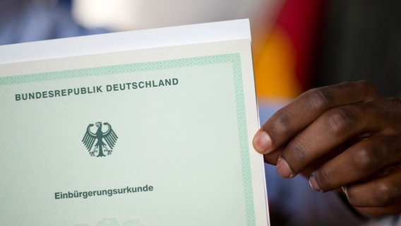 Ein Mann aus Afrika hält seine Einbürgerungsurkunde der Bundesrepublik Deutschland in der Hand. © dpa-Bildfunk Foto: Julian Stratenschulte