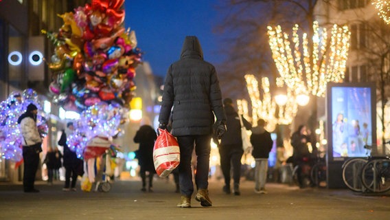 Ein Passant läuft mit einer Einkaufstaschen durch die Innenstadt. © Julian Stratenschulte/dpa Foto: Julian Stratenschulte