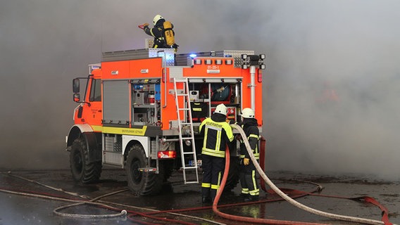 Ein Einsatzfahrzeug der Feuerwehr steht in dicken Rauchschwaden. © NDR Foto: Stefan Rampfel