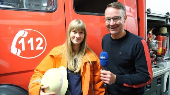 Podcast-Hosts Torben Hildebrandt (rechts) und Märit Heuer stehen vor einem Einsatzfahrzeug der Feuerwehr. © NDR 