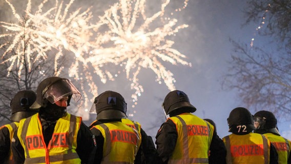Polizisten sind im Einsatz. Im Hintergrund ist ein Feuerwerk zu sehen. © dpa-Bildfunk Foto: Clemens Heidrich
