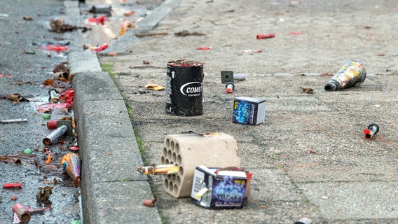 Vermüllte Straßen mit jede Menge Überbleibseln von Feuerwerk, Böllern und Verpackungen auf einer Straße und einem Gehweg. © Picture Alliance Foto: Torsten Sukrow