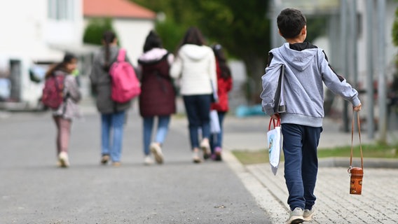 Flüchtlinge gehen in der Landesaufnahmebehörde Niedersachsen am Standort Grenzdurchgangslager Friedland an Unterkünften vorbei. © picture alliance / dpa Foto: Swen Pförtner