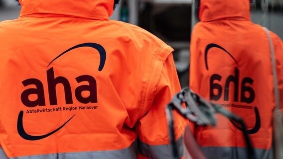 Ein Mann trägt eine Signal-Jacke mit der Aufschrift "aha Abfallwirtschaft Region Hannover". © picture alliance/dpa Foto: Swen Pförtner