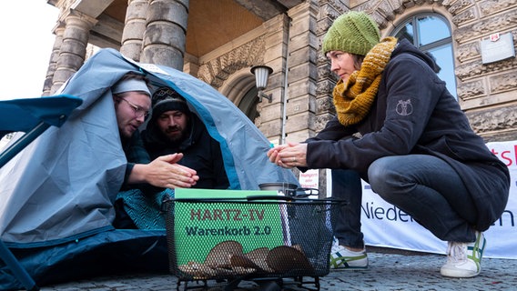 Demonstranten sitzen in einem Zelt und wärmen sich über einem Gaskocher die Hände. © Melissa Erichsen/dpa Foto: Melissa Erichsen