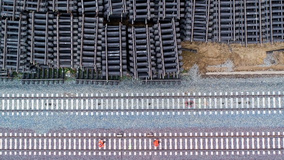 EIn Bild von oben von lagernden Schienen und Arbeitern, die neue Schienen verlegen. © dpa Bildfunk Foto: Julian Stratenschulte