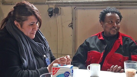 Hamsa Mahamed Hassan und eine Frau sitzen an einem Tisch. © NDR 