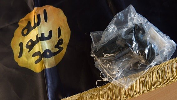 Eine beschlagnahmte Waffe liegt während einer Pressekonferenz der Polizei in Göttingen auf einer IS-Flagge. © dpa-Bildfunk Foto: Swen Pförtner