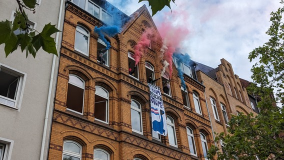 Aus mehreren Fenstern eines Mehrfamilienhaus steigt roter und blauer Rauch auf. Vermummte stehen an den Fenstern. Aus einem der Fenster hängt ein Banner mit der Aufschrift "Unsere Träume brauchen Räume". © NDR Foto: Kaspar Weist