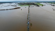 Kirchwahlingen: Fahrzeuge vom THW sowie der Feuerwehr fahren auf einer teilweise überfluteten Straße unweit der Aller (Aufnahme mit einer Drohne). © dpa-Bildfunk Foto: Philipp Schulze