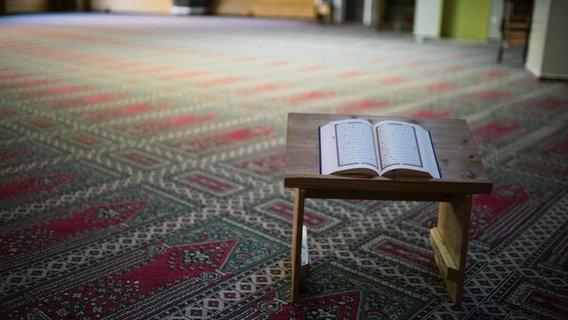 Ein Koran auf Koranständer und einem Gebetsteppich in einer Moschee. © NDR Foto: Julius Matuschik