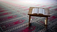 Ein Koran auf Koranständer und einem Gebetsteppich in einer Moschee. © NDR Foto: Julius Matuschik