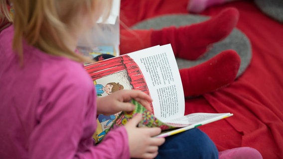 Ein Mädchen liest in einer Kita in einem Buch. © picture alliance / dpa Foto: Daniel Reinhardt