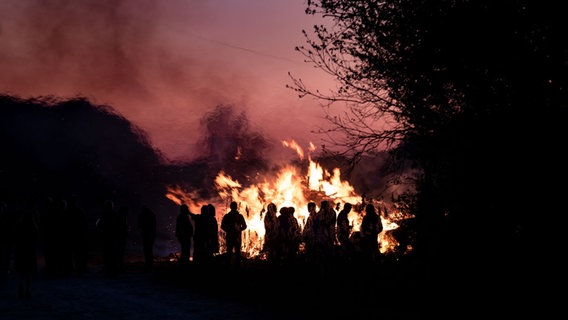 Loderndes Osterfeuer, davor Menschen als Scherenschnitt erkennbar. © dpa-Bildfunk Foto: Peter Steffen