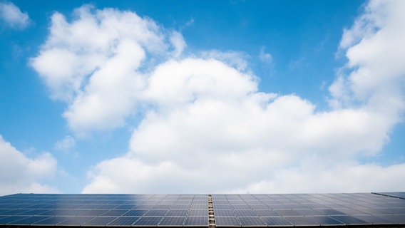 Solaranlage auf einem Dach, darüber blauer Himmel mit Wolken. © picture alliance Foto: Julian Stratenschulte