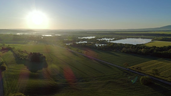 Eine Luftaufnahme zeigt einen Sonnenaufgang über einer ländlichen Gegend. © NDR Foto: Jannes Kuhlmann