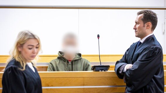Hannover: Der Angeklagte sitzt beim Prozessauftakt in einen Saal vom Landgericht Hannover, seine Verteidiger stehen vor ihm. © dpa-Bildfunk Foto: Moritz Frankenberg