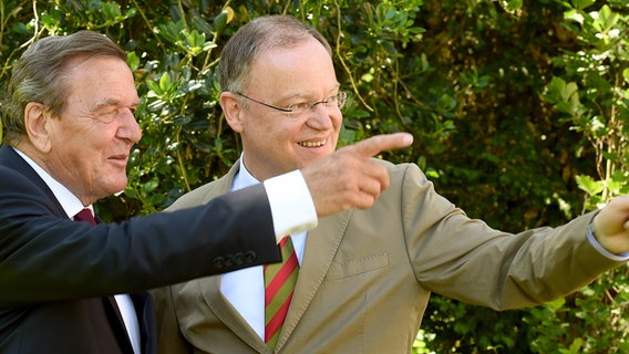 Gerhard Schröder und Stephan Weil (SPD) zeigen in einem Garten mit Händen aus dem Bild. © picture alliance Foto: Holger Hollemann