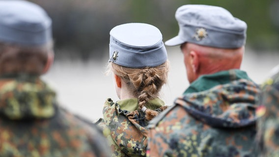 Drei Reservisten der Bundeswehr stehen mit dem Rücken zur Kamera. © picture alliance/dpa Foto: Tobias Hase