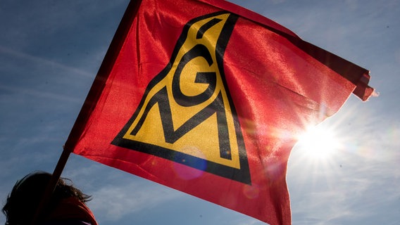 Ein Mensch hält eine Flagge der IG Metall bei Sonnenschein. © picture alliance/dpa/Daniel Bockwoldt Foto: Daniel Bockwoldt