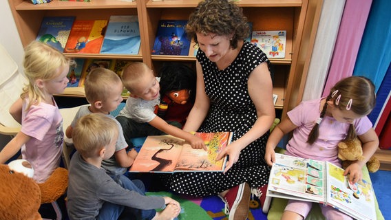 Eine Sprachfachkraft liest mit Kindern zusammen in einer Kita Bücher. © picture alliance/dpa | Waltraud Grubitzsch Foto: Waltraud Grubitzsch