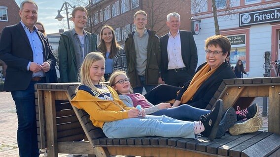 Ministerin Honé (SPD) sitzt mit Kinderbürgermeisterinnen der Stadt Bramsche auf einer Bank. © MB 