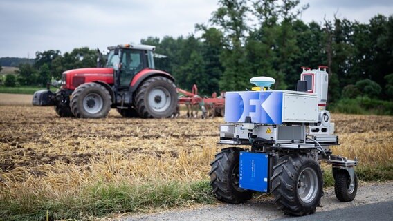 Ein moderner Agritech-Roboter steht vor einem Traktor. © Deutsches Forschungszentrum für Künstliche Intelligenz 