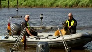Zwei Polizisten fahren mit einem Polizeihund auf einem Boot über die Oste. © NDR 